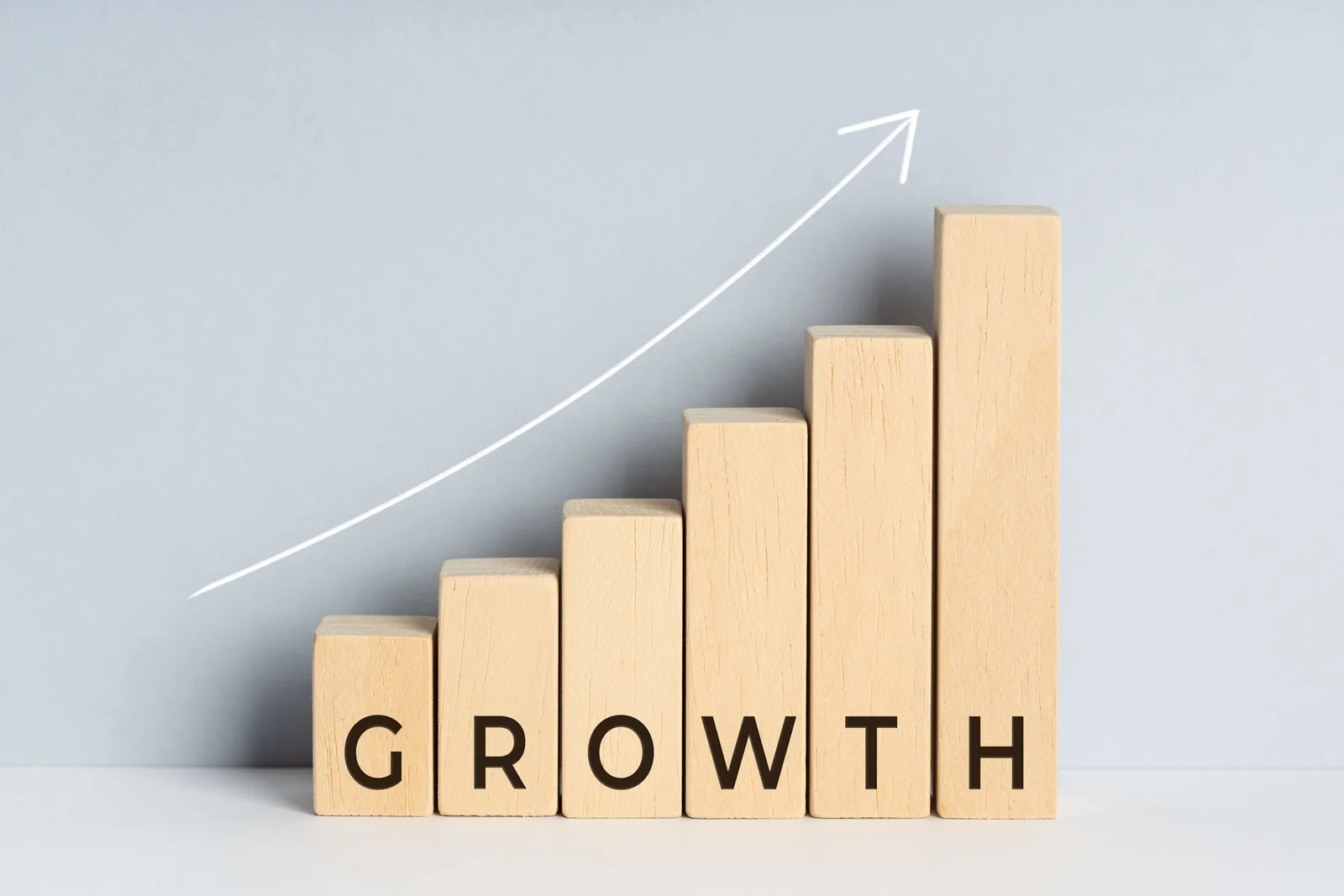 Growth concept. Wooden block bar chart graph with text and upward trend line drawn on background.