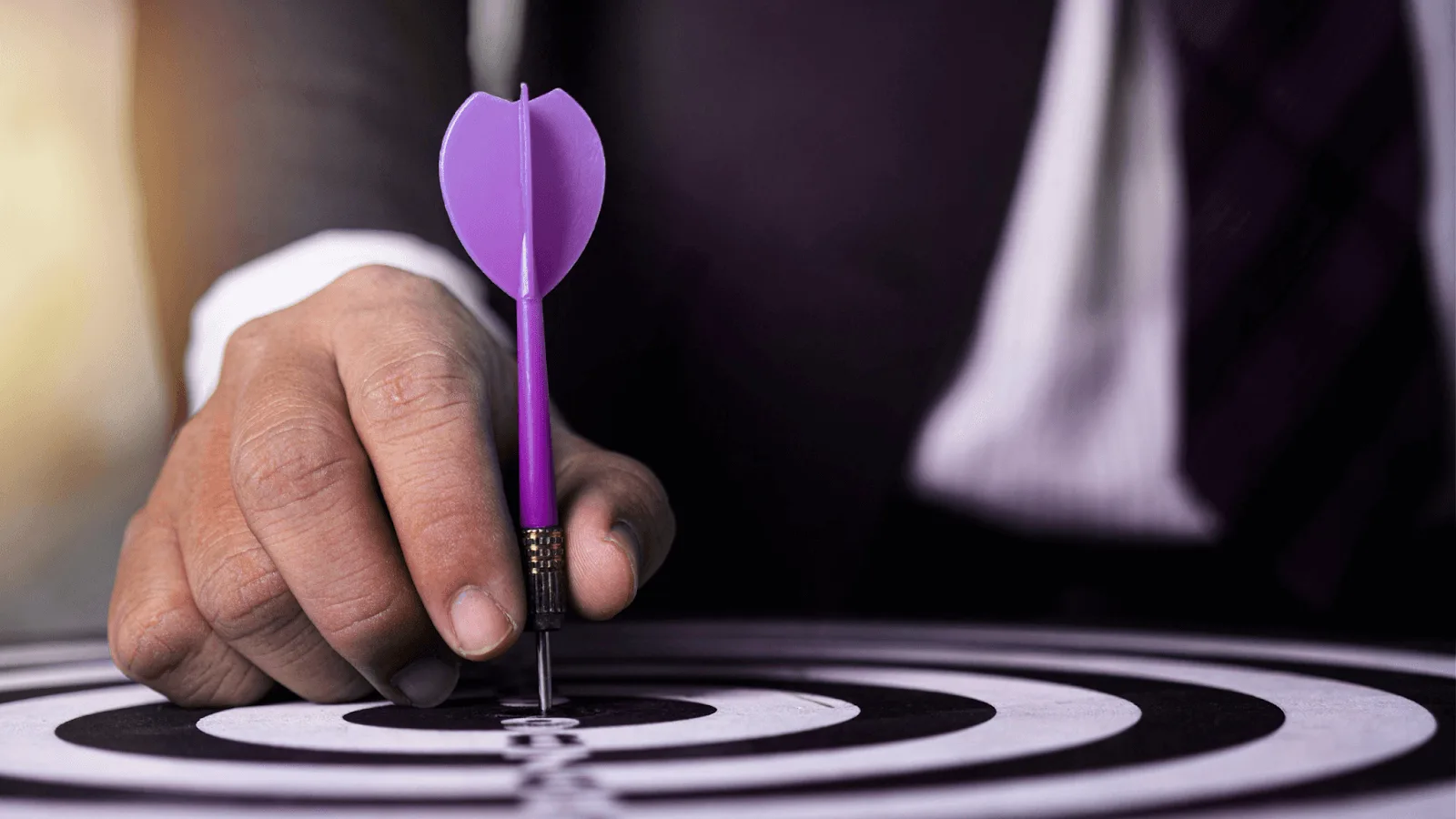 c businessman placing a purple dart in the bullseye of a target, representing precision, goal achievement, and strategic business focus.