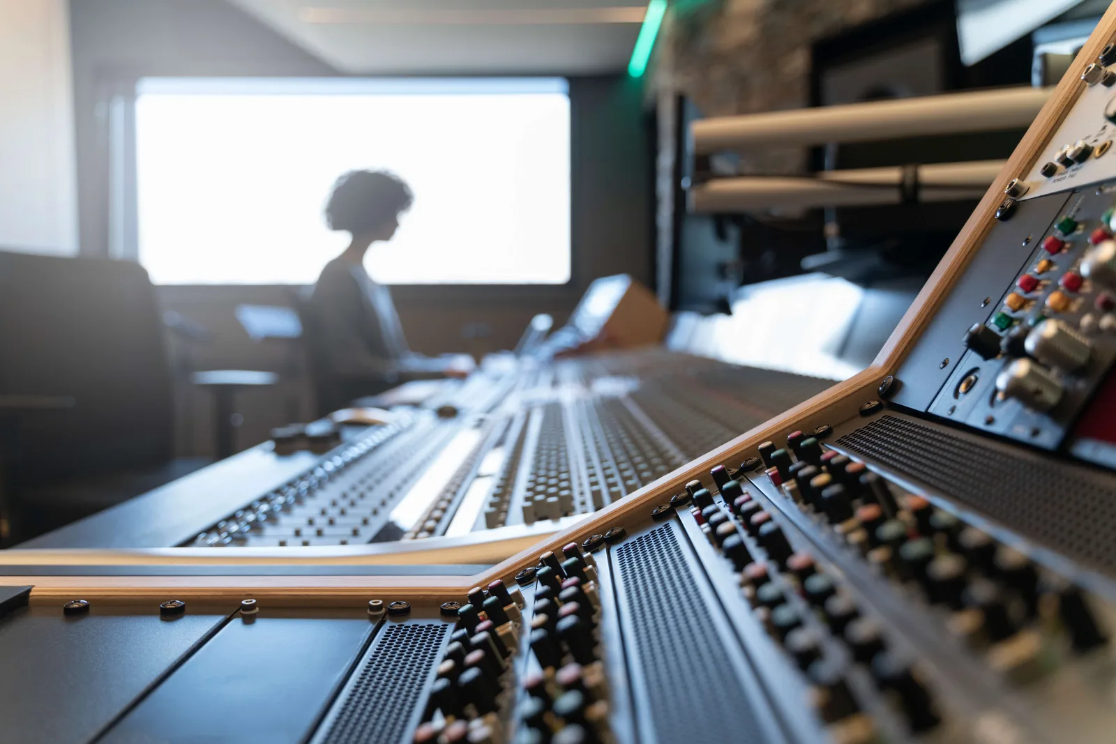 Control panel of a music recording studio with a woman in the background