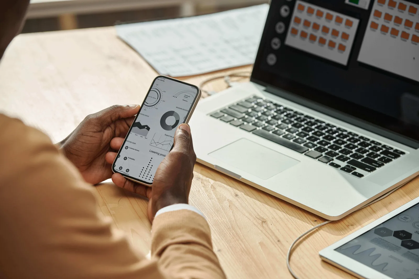 Close-up of businessman examining graphs on his smartphone while working on laptop at table