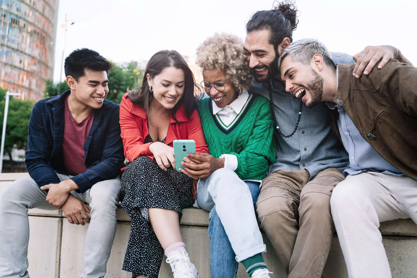 Group of happy multi ethnic friends sharing social media content on smart phone