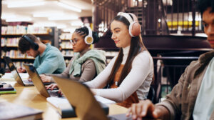 People, studying and laptop in library with headphones, planning and working on research assignment.